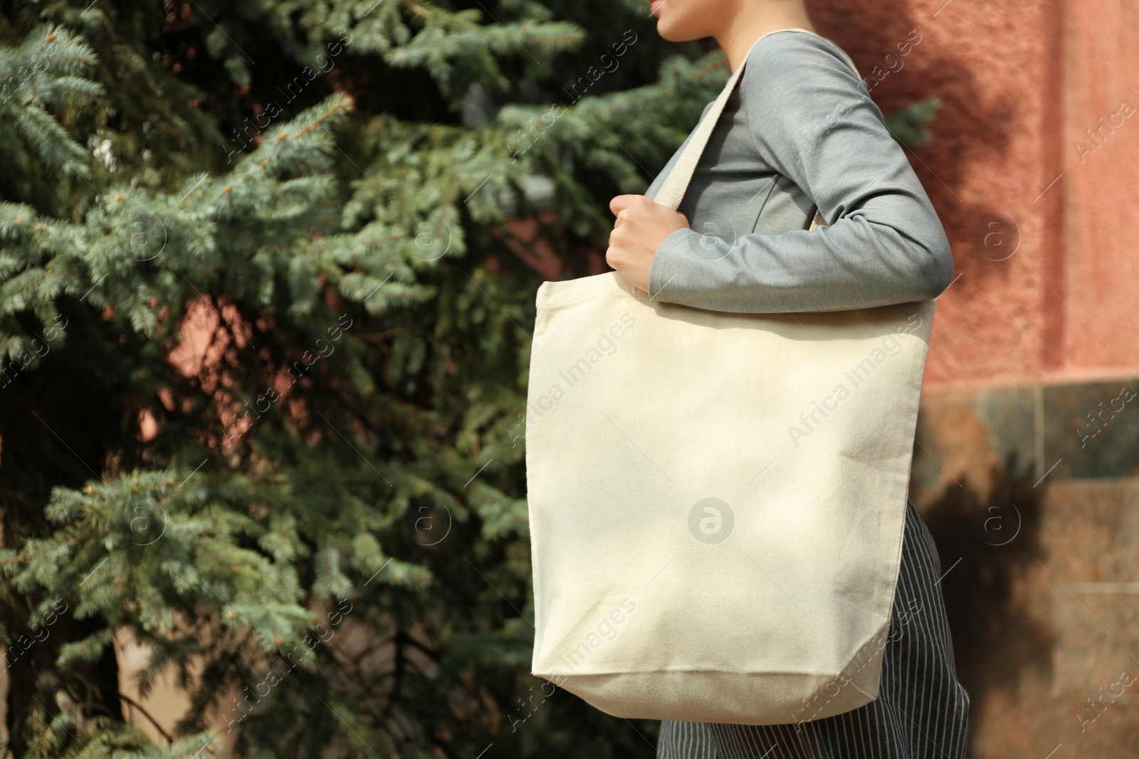 Photo of Young woman with cotton bag on city street, closeup. Mockup for design