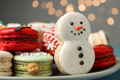 Beautifully decorated Christmas macarons on table against blurred festive lights, closeup