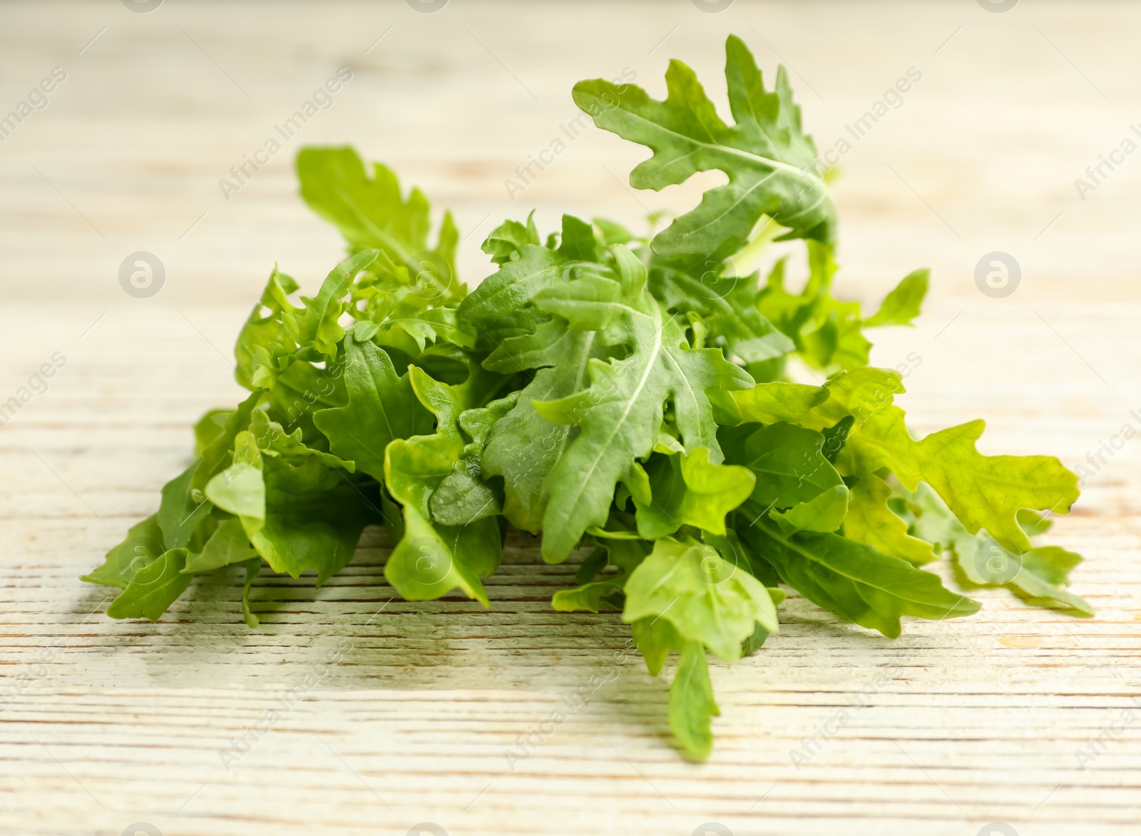 Photo of Fresh arugula on white wooden table, closeup