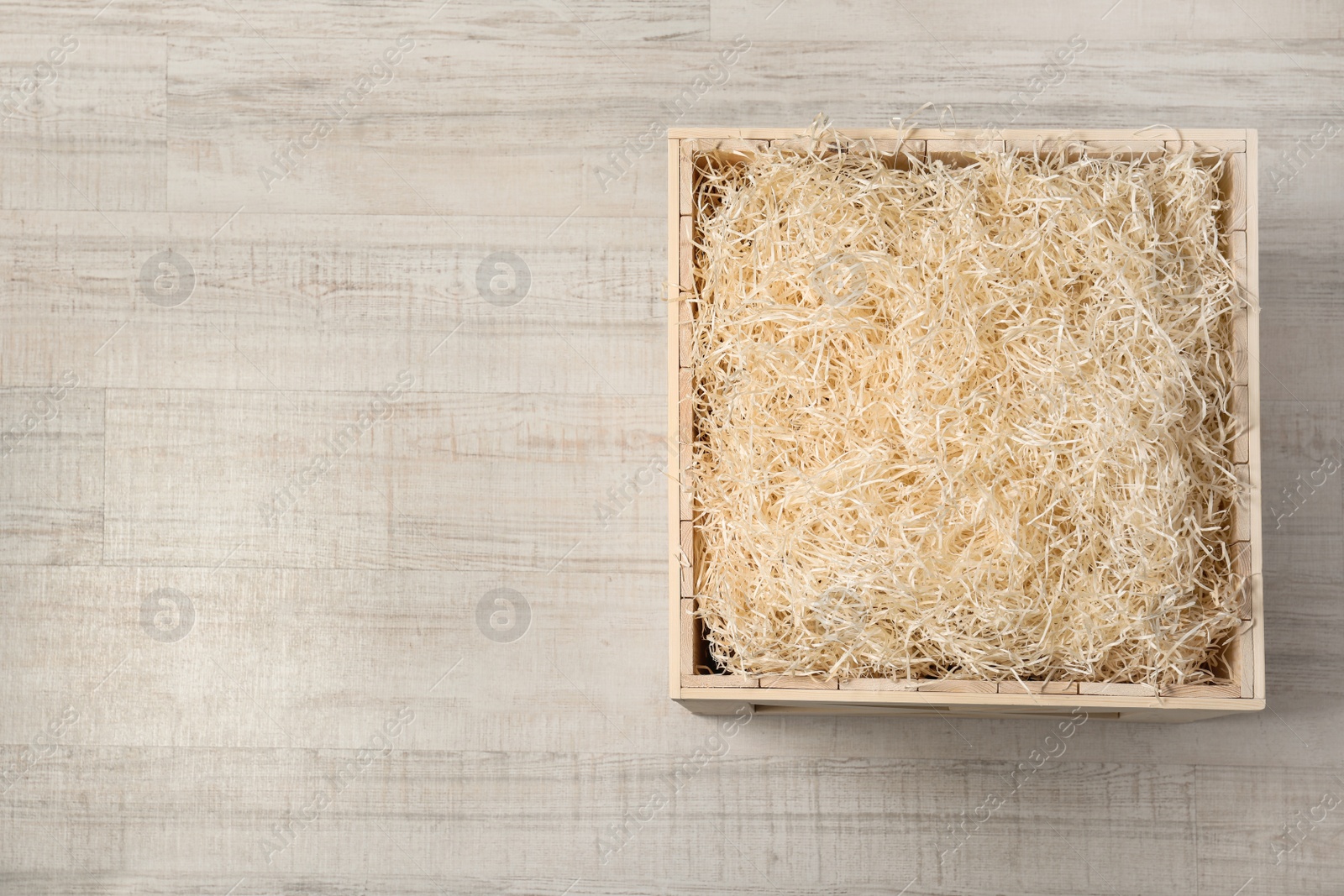 Photo of Wooden crate with filler on light background, top view. Space for text