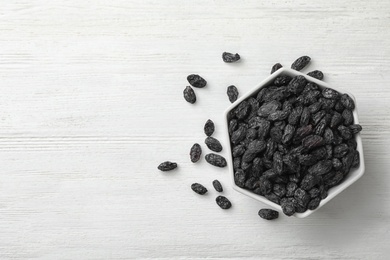 Photo of Bowl of raisins on wooden background, top view with space for text. Dried fruit as healthy snack