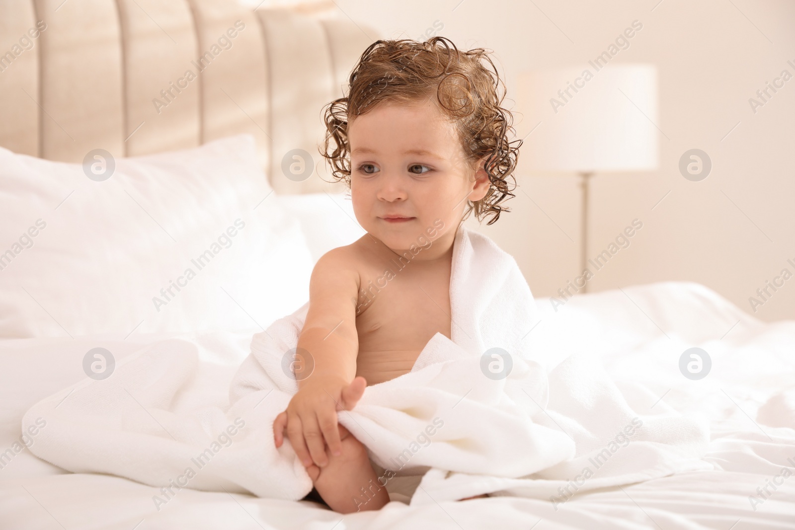 Photo of Cute little baby with soft towel on bed after bath