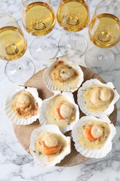 Photo of Fried scallops in shells and wine on white marble table, above view