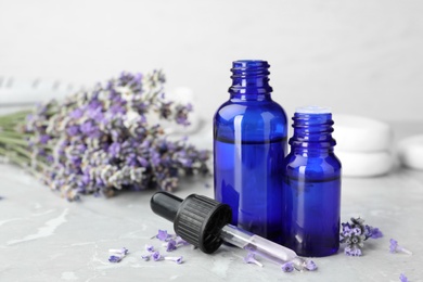 Photo of Bottles with natural lavender essential oil on table, space for text