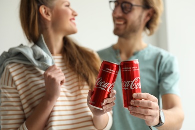 Photo of MYKOLAIV, UKRAINE - NOVEMBER 28, 2018: Young couple with Coca-Cola cans indoors