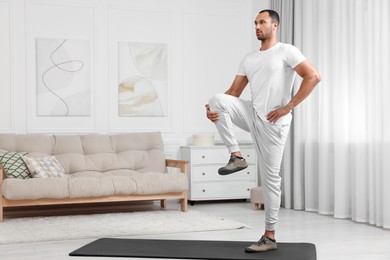 Photo of Man doing morning exercise on fitness mat at home