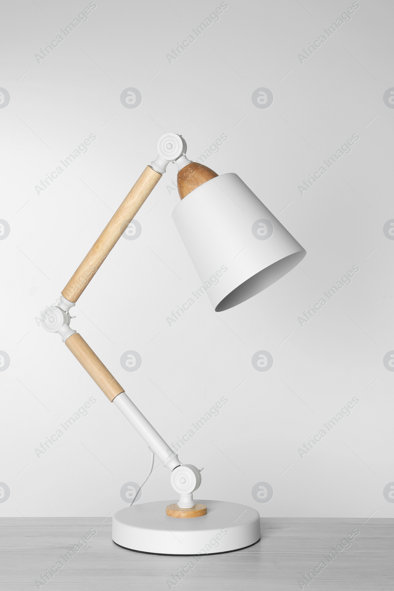 Photo of Stylish modern desk lamp on white wooden table