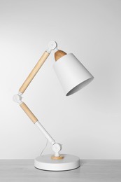 Photo of Stylish modern desk lamp on white wooden table