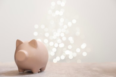 Photo of Piggy bank on grey table against blurred lights, space for text