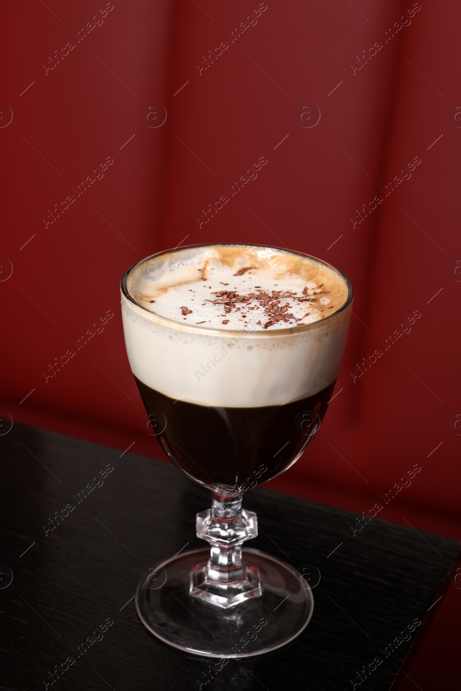 Photo of Glass of aromatic coffee with chocolate powder on black table in cafe