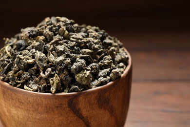 Photo of Bowl of Tie Guan Yin oolong tea leaves on wooden background, closeup. Space for text