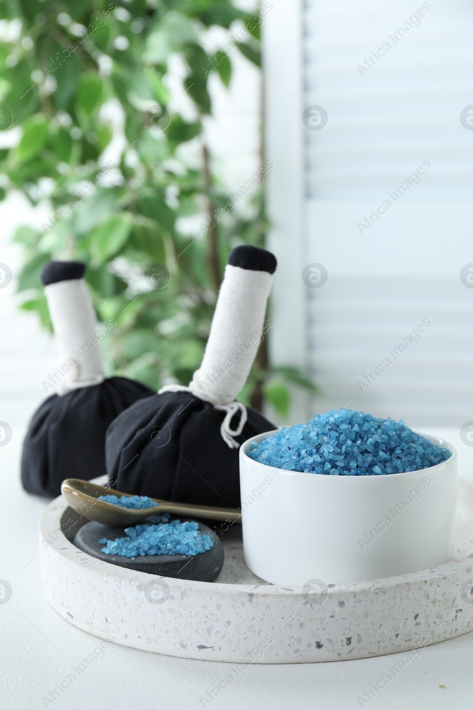 Photo of Blue sea salt and herbal bags on white table indoors, space for text