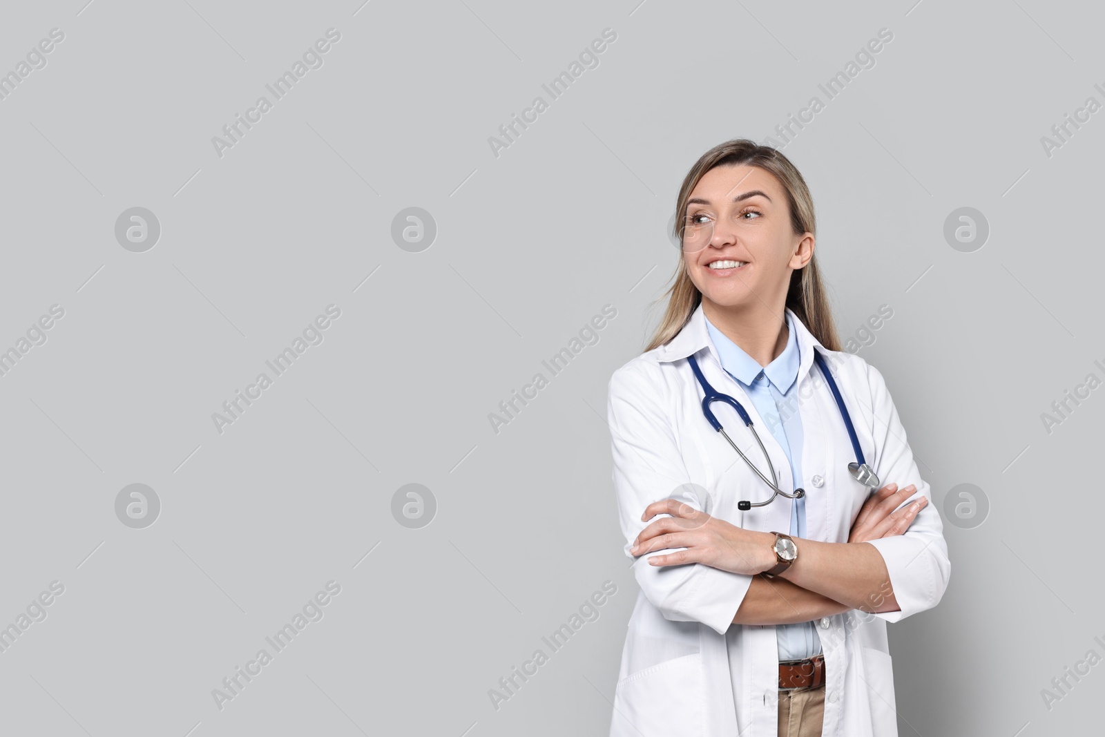 Photo of Portrait of happy doctor with stethoscope on light grey background, space for text