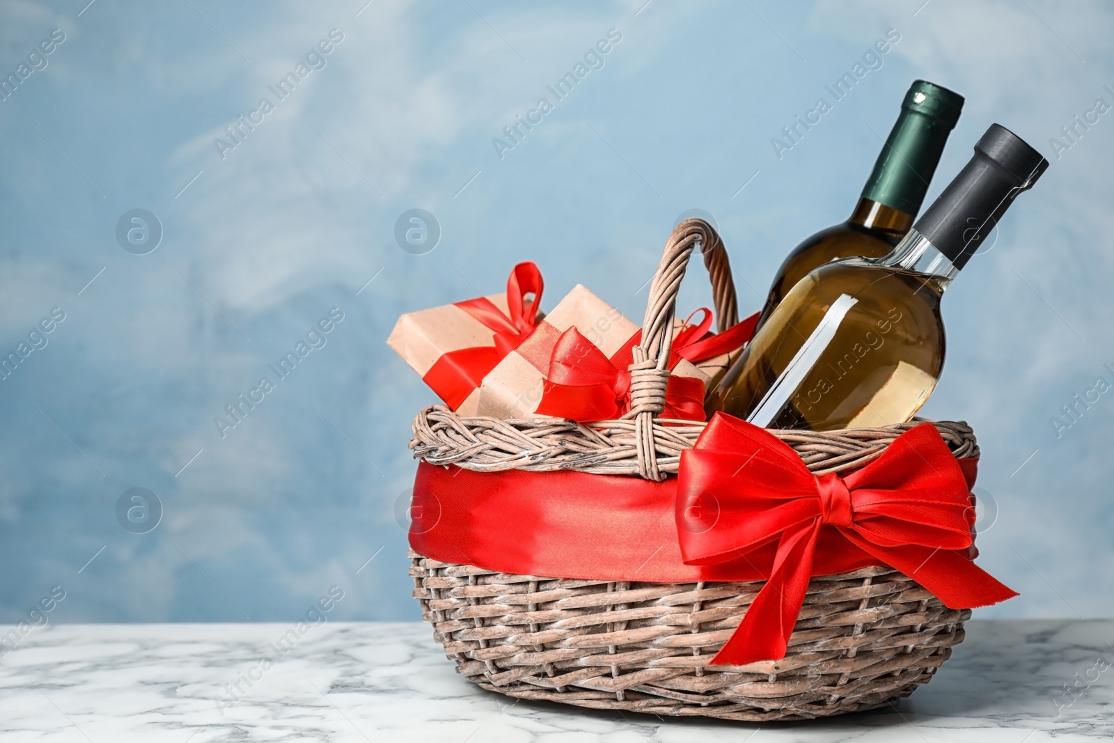 Photo of Gift basket with bottles of wine on color background. Space for text