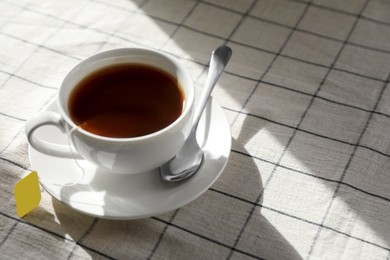 Photo of Bag of black tea in cup on table. Space for text
