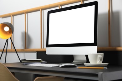 Modern computer with blank screen on black table indoors. Mockup for design