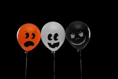 Photo of Spooky balloons for Halloween party on black background