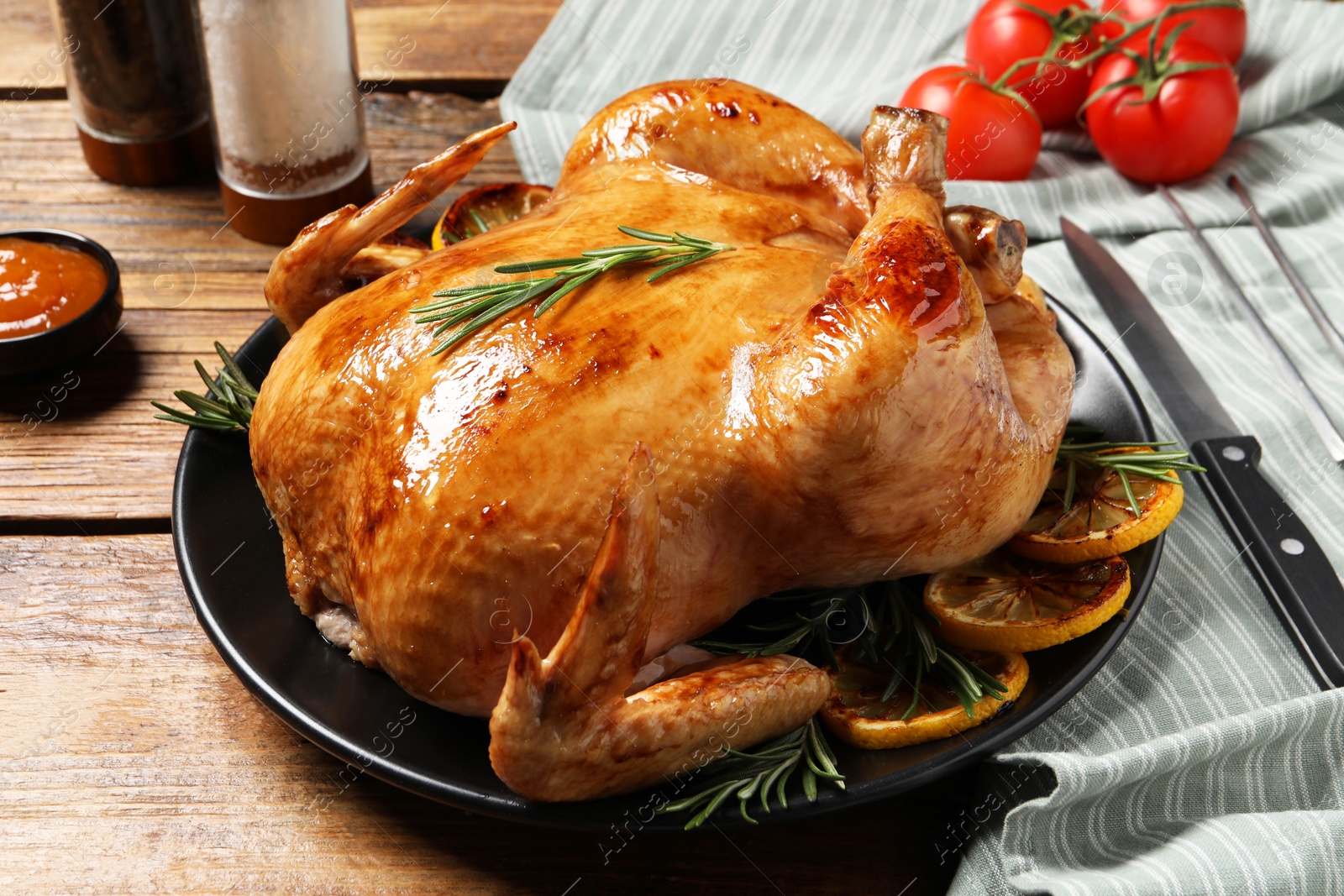 Photo of Tasty roasted chicken with rosemary and lemon on wooden table