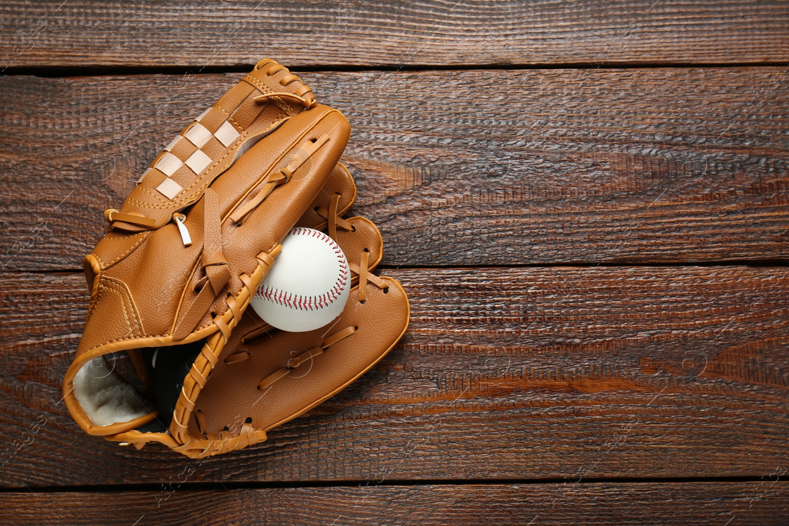 Photo of Leather baseball glove with ball on wooden table, top view. Space for text