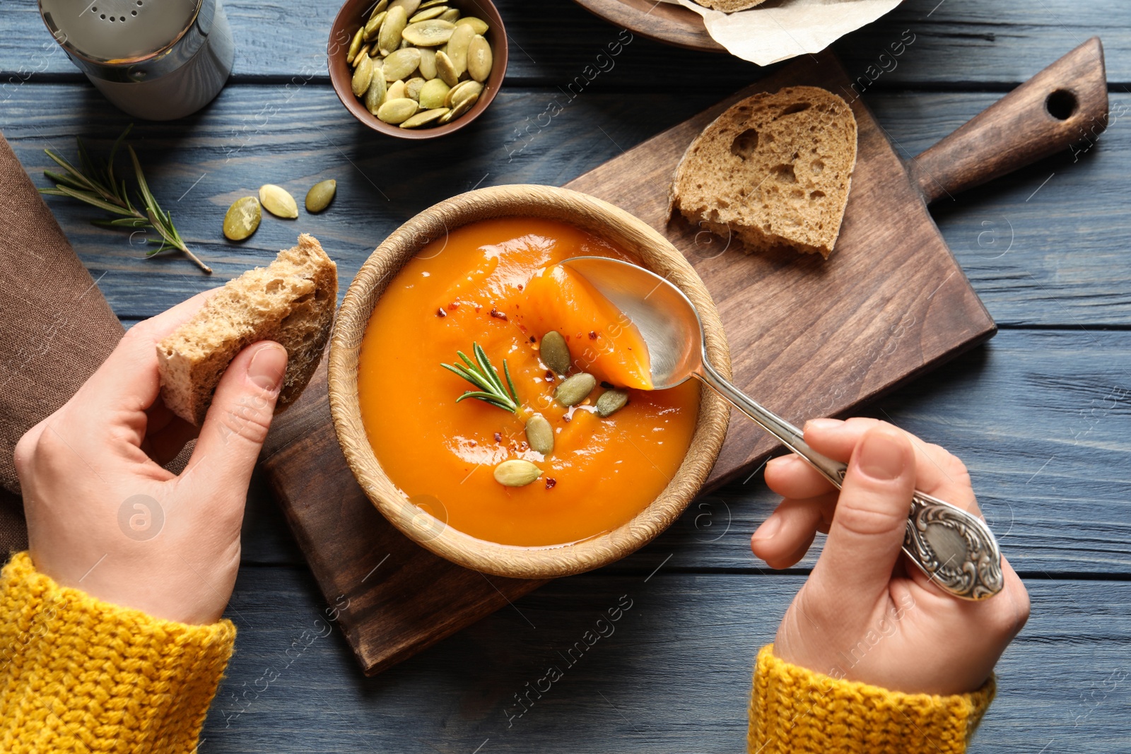 Photo of Woman eating sweet potato soup at table, top view