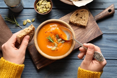 Photo of Woman eating sweet potato soup at table, top view