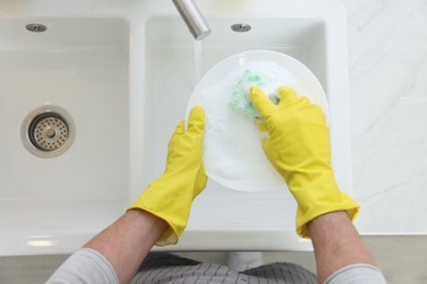 Photo of Man washing plate in kitchen sink, above view