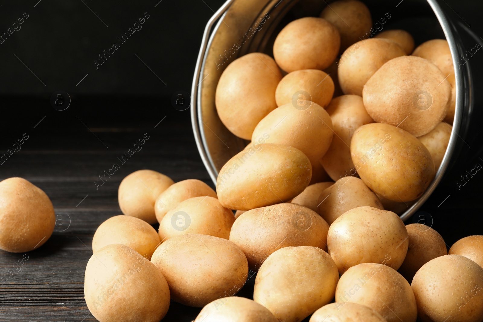 Photo of Raw fresh organic potatoes on black wooden table, closeup