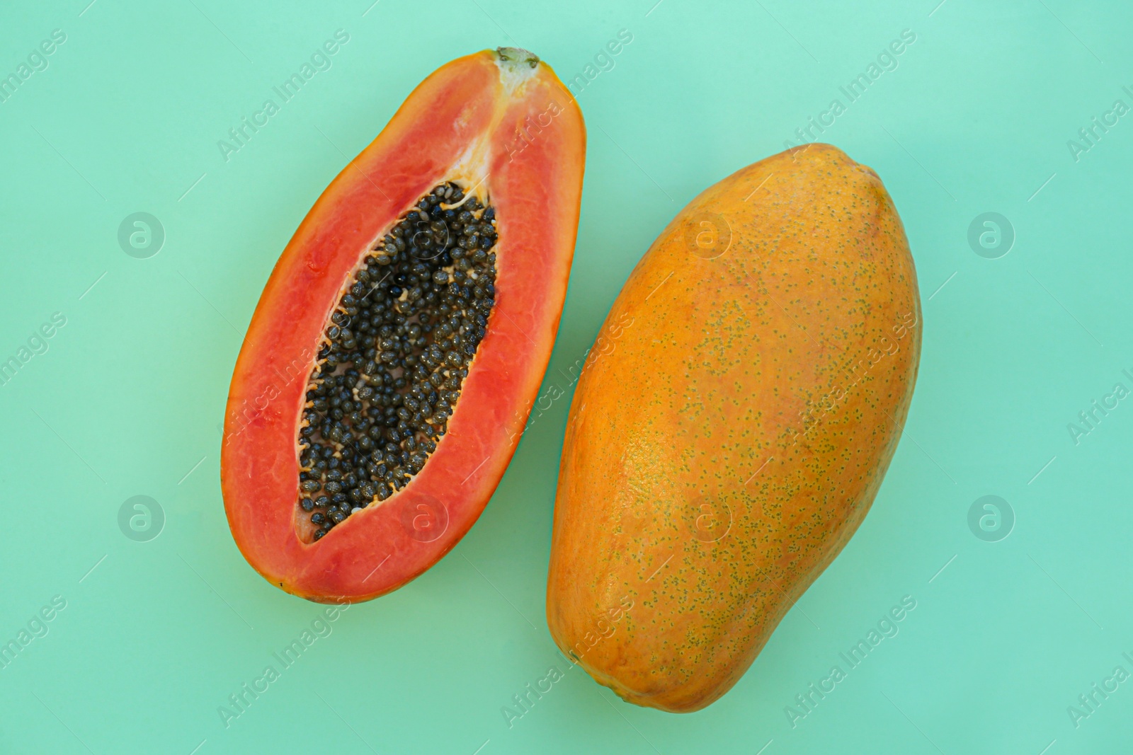 Photo of Fresh ripe papaya fruits on light turquoise background, flat lay