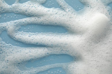 Photo of White washing foam on color background, top view