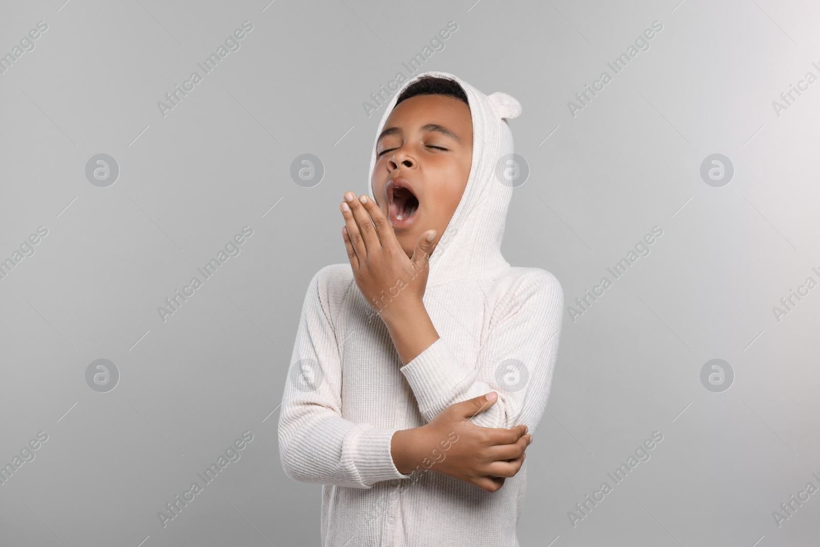 Photo of Boy in pajama yawning on grey background. Insomnia problem