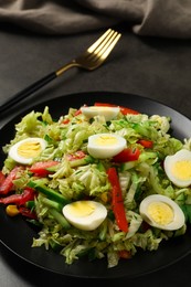Photo of Delicious salad with Chinese cabbage and quail eggs served on black table, closeup