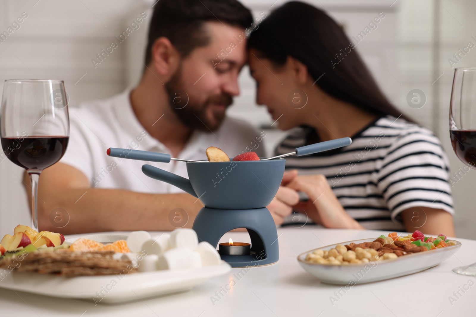 Photo of Romantic date with fondue. Couple enjoying each other at home, selective focus