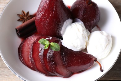 Photo of Tasty red wine poached pears and ice cream in bowl on table, above view