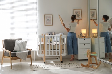 Photo of Decorator hanging pictures on wall in baby room. Interior design