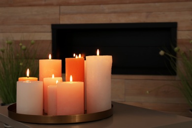Tray with burning candles on table in living room