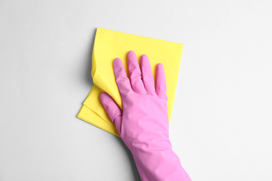 Photo of Person in rubber glove with rag on light grey background, closeup of hand