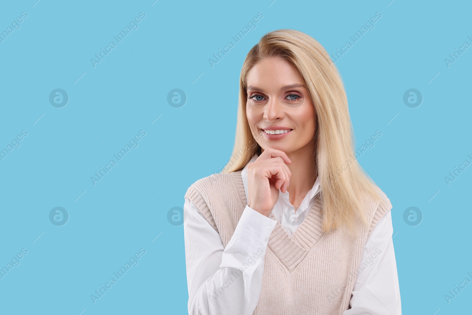 Photo of Portrait of smiling middle aged woman on light blue background. Space for text