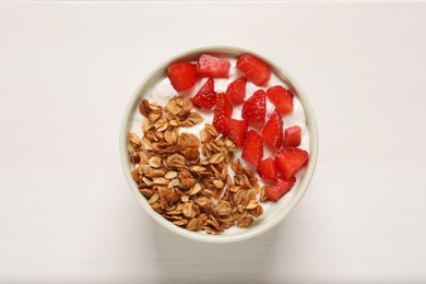 Photo of Yogurt served with granola and strawberries on white wooden table, top view