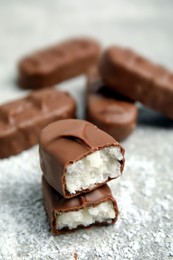 Delicious milk chocolate candy bars with coconut filling on grey table, closeup