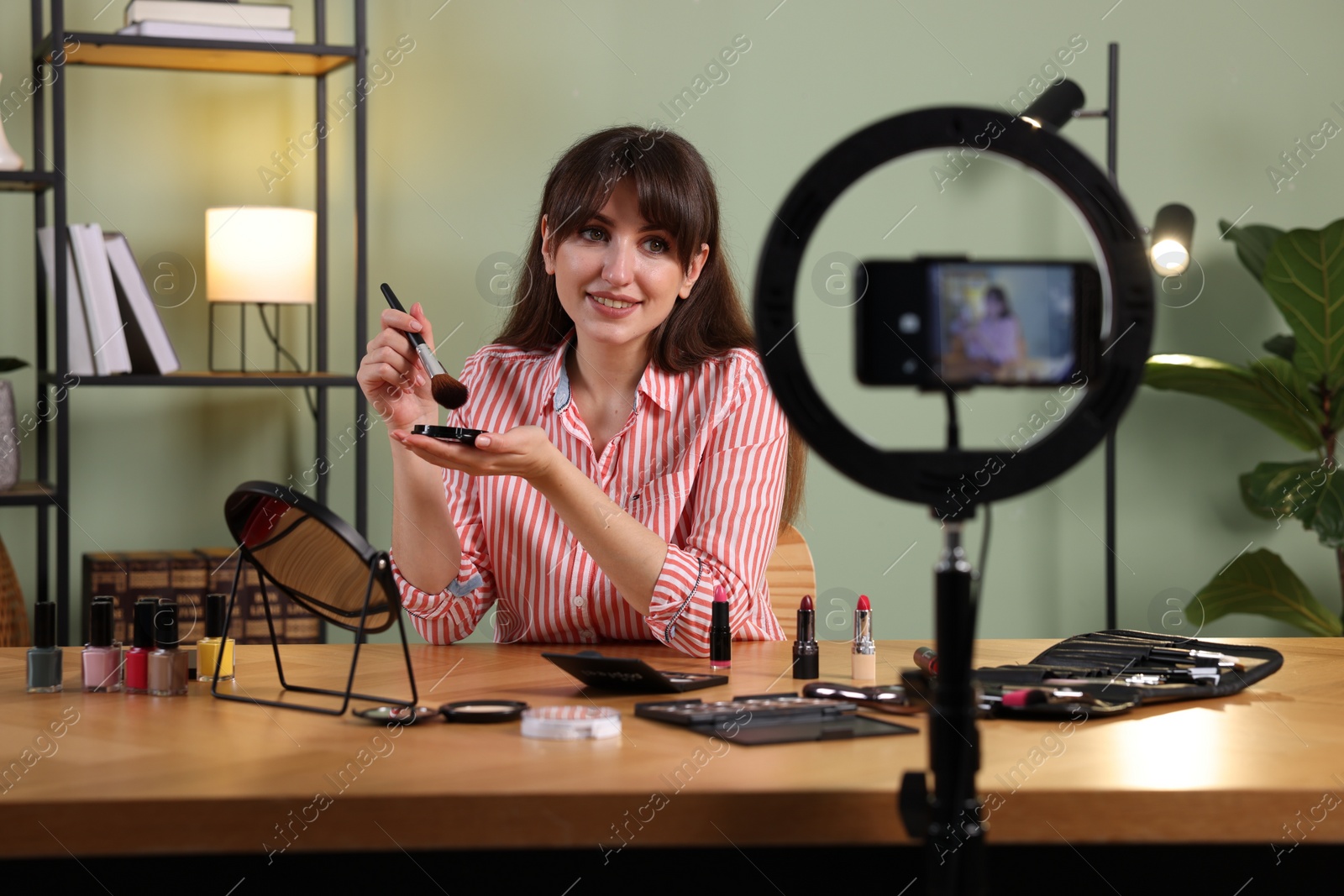 Photo of Smiling beauty blogger recording makeup tutorial at home