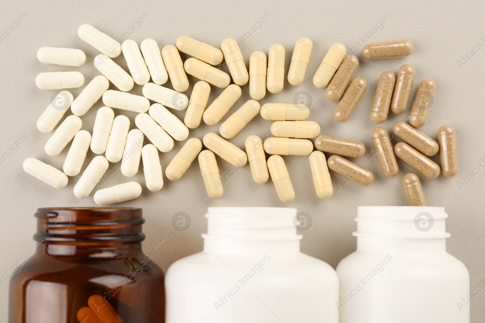 Photo of Bottles and different vitamin capsules on light background, flat lay