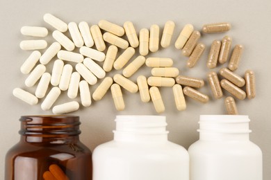 Bottles and different vitamin capsules on light background, flat lay