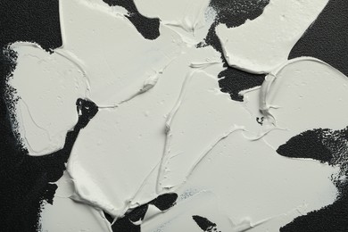 Photo of Strokes of white oil paint on black canvas, closeup