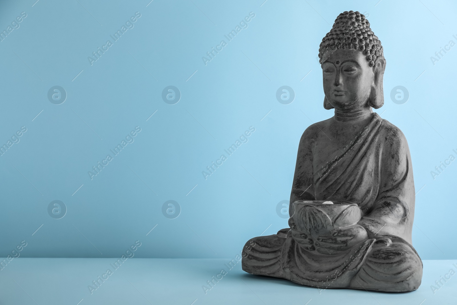 Photo of Beautiful stone Buddha sculpture on light blue background. Space for text