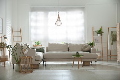 Photo of Stylish living room interior with comfortable grey sofa and plants