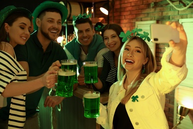 Photo of People with beer taking selfie in pub. St Patrick's day celebration
