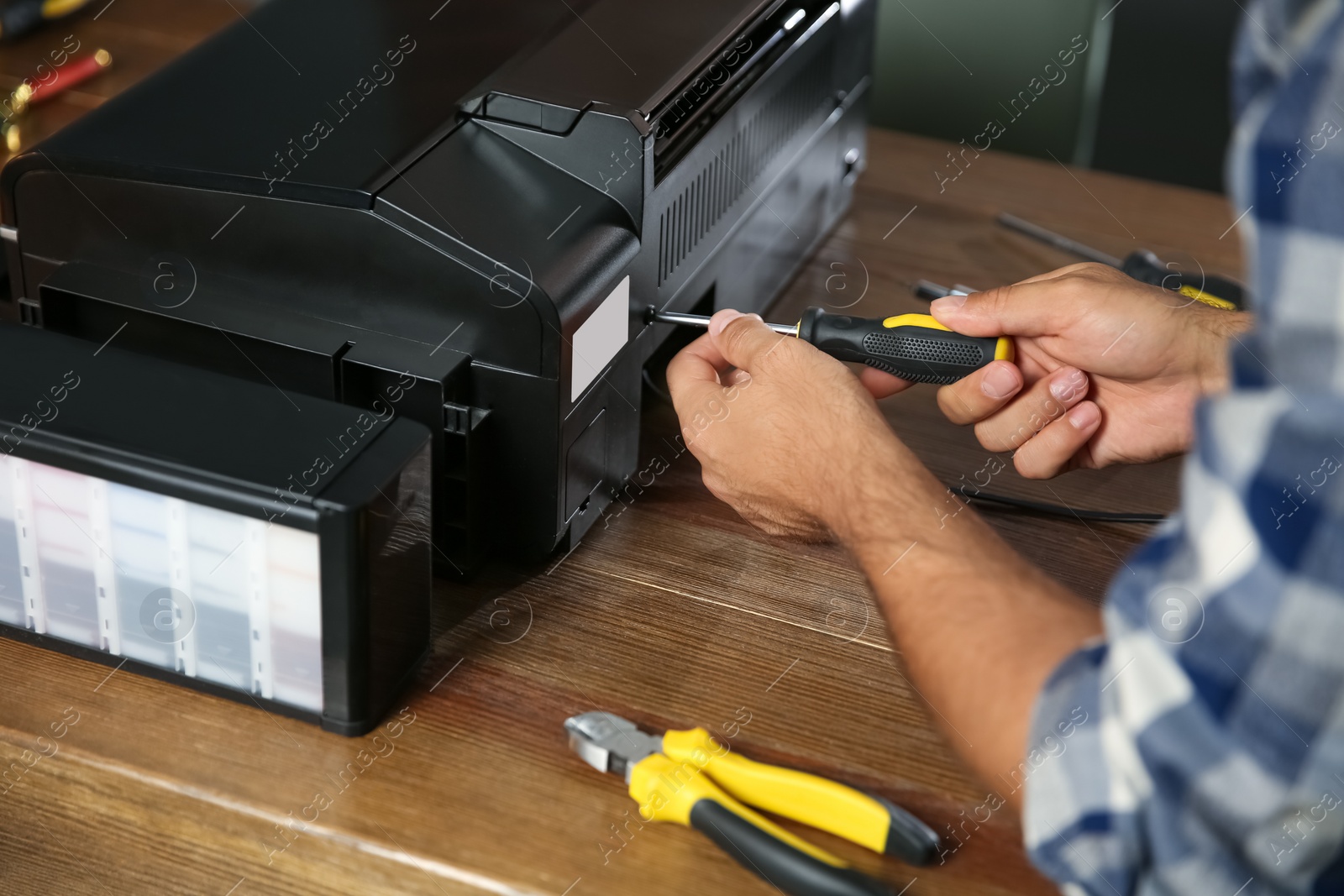 Photo of Repairman with screwdriver fixing modern printer indoors, closeup