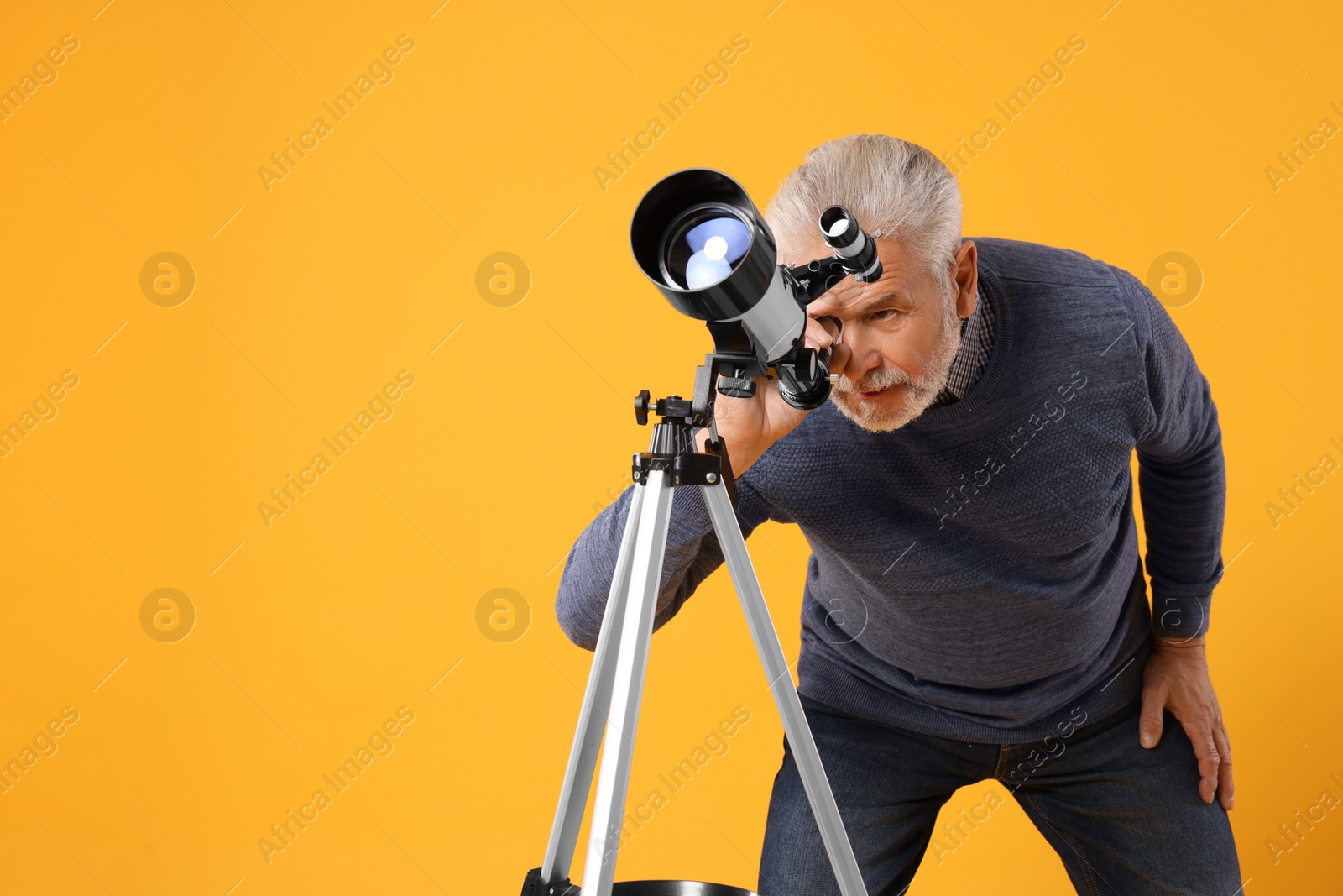 Photo of Senior astronomer looking at stars through telescope on yellow background, space for text