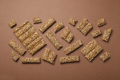 Pieces of delicious kozinaki bars on brown background, flat lay