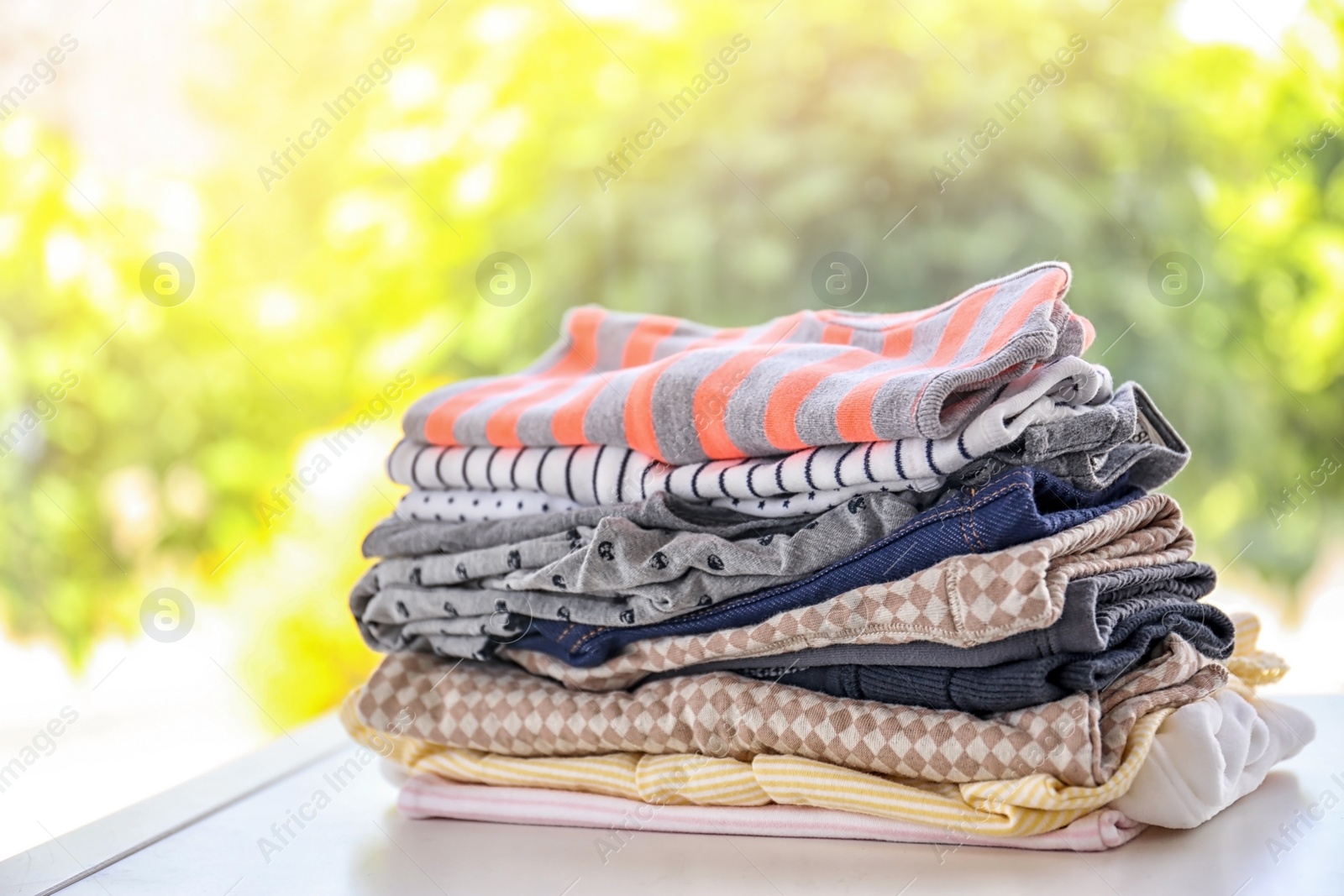 Photo of Stack of stylish child clothes on table against blurred background